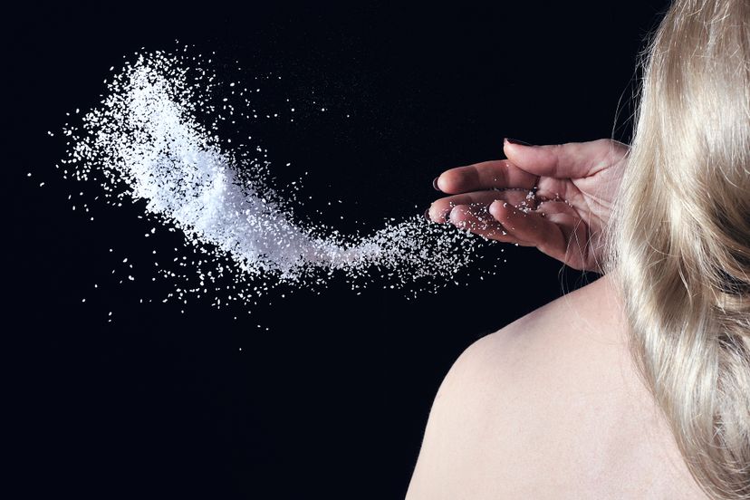 Woman throwing salt over her left shoulder.