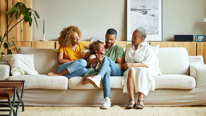 Cheerful boy with parents and grandmother on sofa.