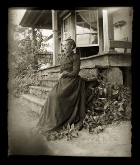 Woman wearing Victorian-era clothing. Taken on the front porch of her farmhouse.