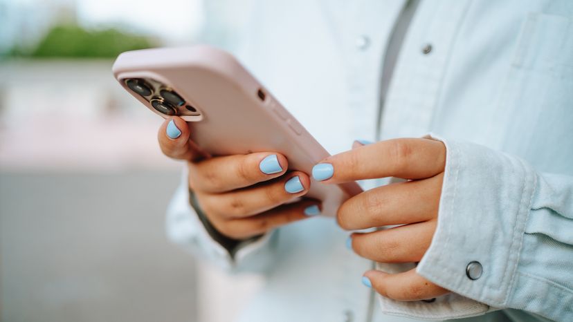 Close-up of person with blue nail polish holding a smart phone