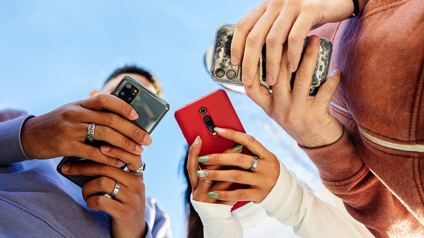 Low angle view of three people using smart phones outdoors