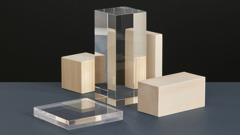 Glass and wooden prisms on a grey surface with black backdrop