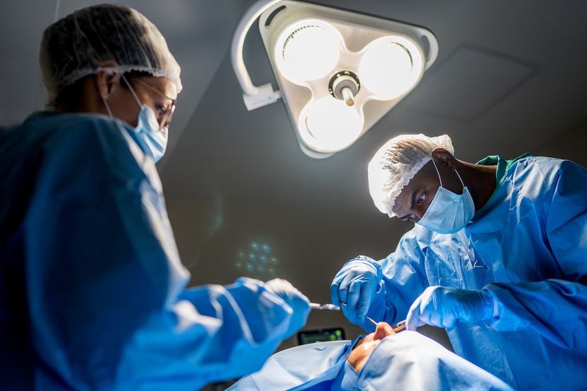 surgeon performing surgery in operating room together with scrub nurse