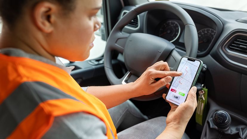 Delivery van driver checking the route map on her mobile phone