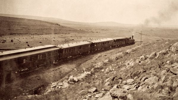 Vintage sepia tone photo of a train going through a desert