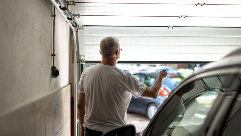 Man with eyeglasses closing and opening garage door with remote controller