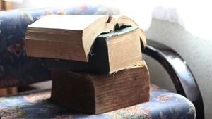 Three thick, old books stacked on a chair