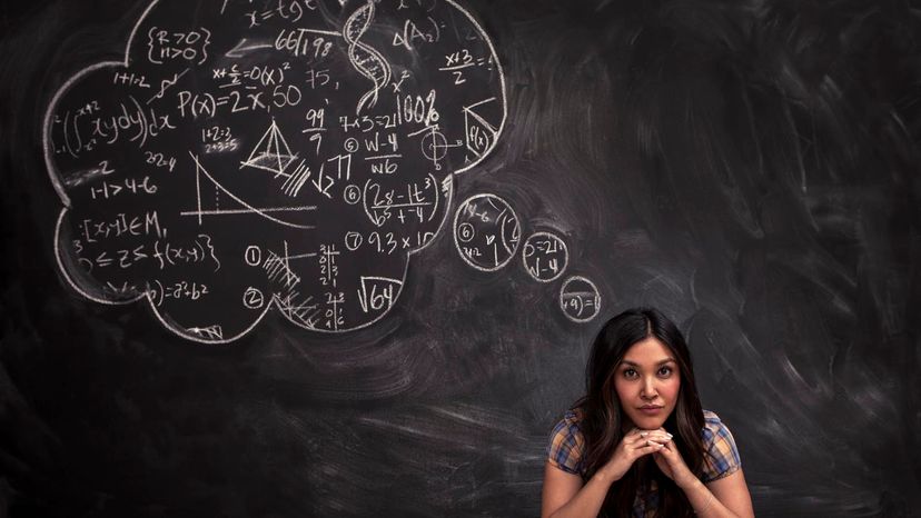 Woman sitting in front of blackboard with chalk thought bubble