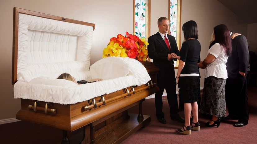 A receiving line of guests next to the casket at a funeral in a funeral home.