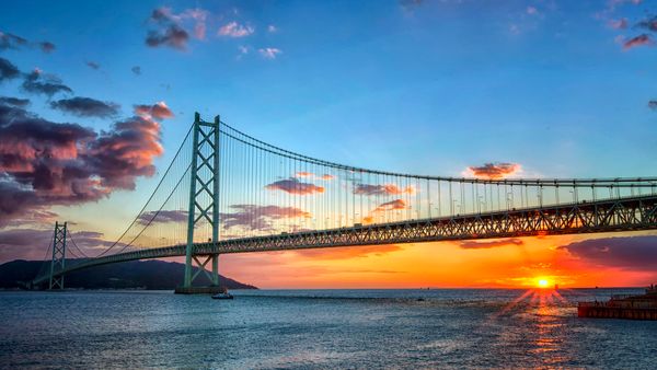 Long suspension bridge over water at sunset