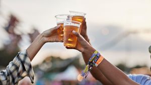 Three people toasting with plastic cups of beer