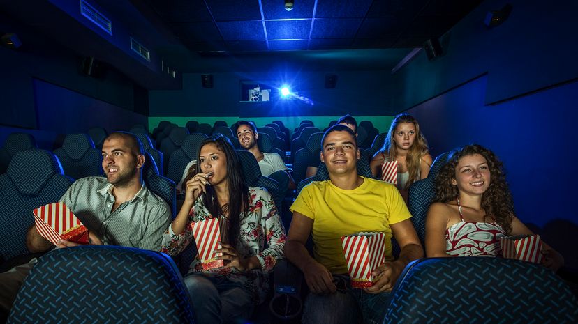 Group of young people watching a movie in a cinema, having fun.
