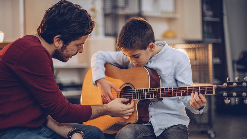 Man teaching boy how to play guitar