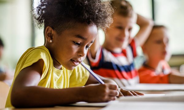 Girl writing with a pencil in the classroom