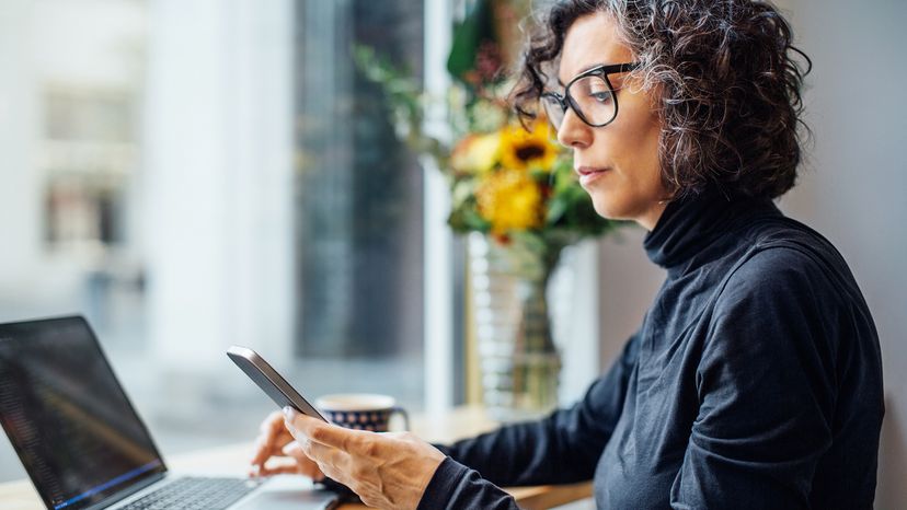 Woman working on laptop and using her phone