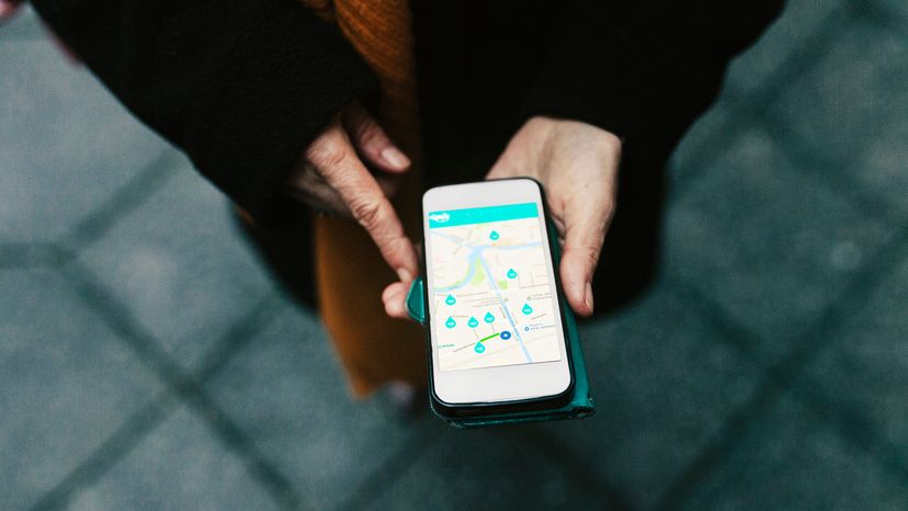 An aerial view of a woman using a car sharing app on her smartphone.