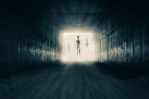 A group of aliens emerging from the light at the end of a dark, sinister tunnel.