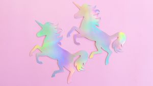 Holographic rainbow unicorns on a pink background.
