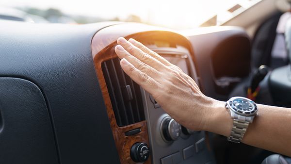 Hand feeling air vent in car, checking for cold air