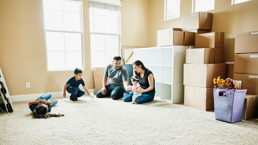 Family sitting on floor of living room of new home during move in day