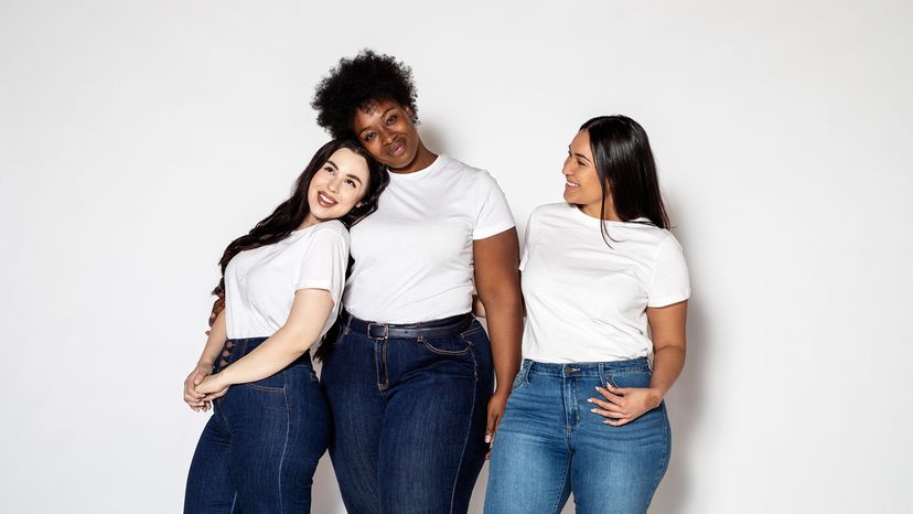 Women in white tees and blue jeans standing against a white background