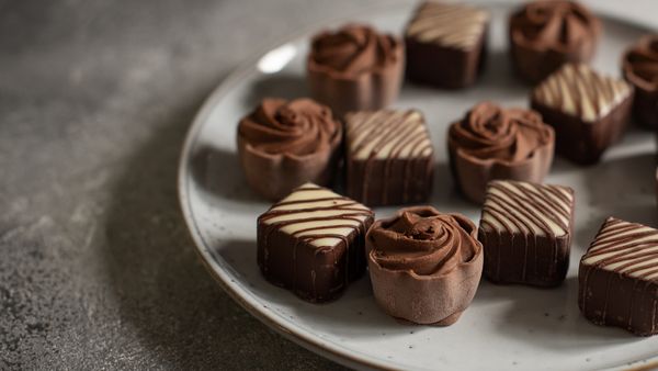 Chocolate truffles on a clean plate. One chocolate is slightly white on the outside.