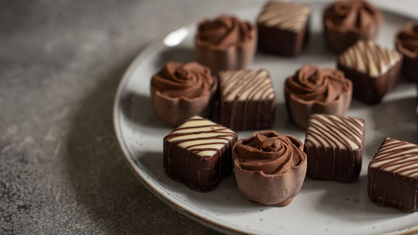 Chocolate truffles on a clean plate. One chocolate is slightly white on the outside.