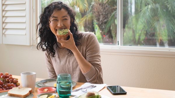 Smiling woman eating avocado toast