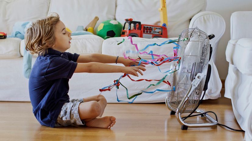 Young boy sitting in front of a fan, desperate for the cool air