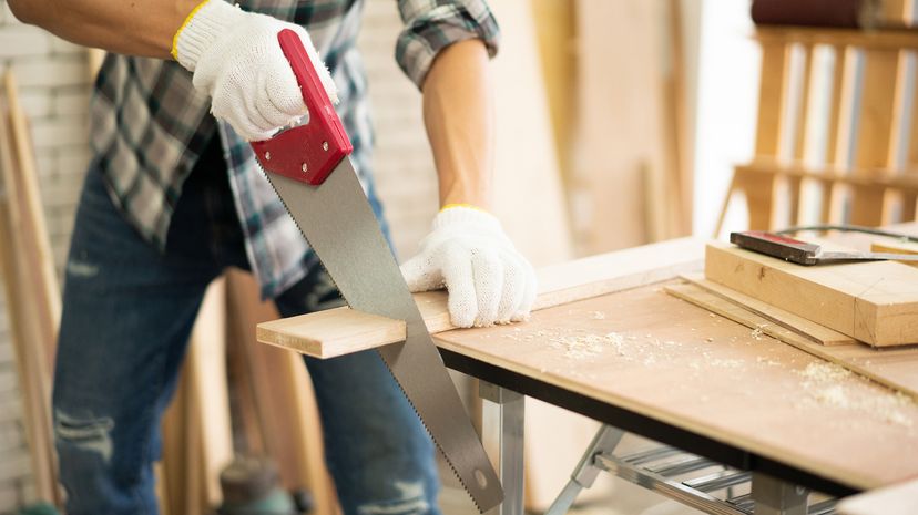 Man cutting a plank of wood with a crosscut saw