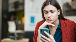 Woman expressing concerned while looking at her phone