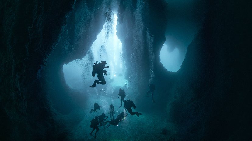 silhouetted scuba divers in deep water