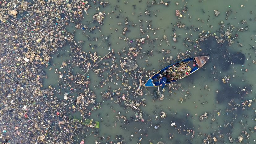 Birds-eye view of a boat rowing through murky waters and tons of trash