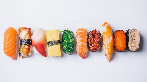 overhead view of variety of sushi on against a white background