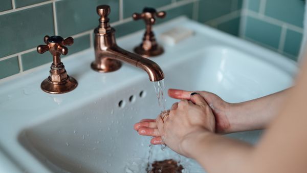 Woman washing hands in sink with running water