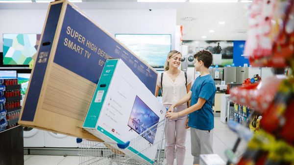 Woman and boy with large TV sets a shopping cart