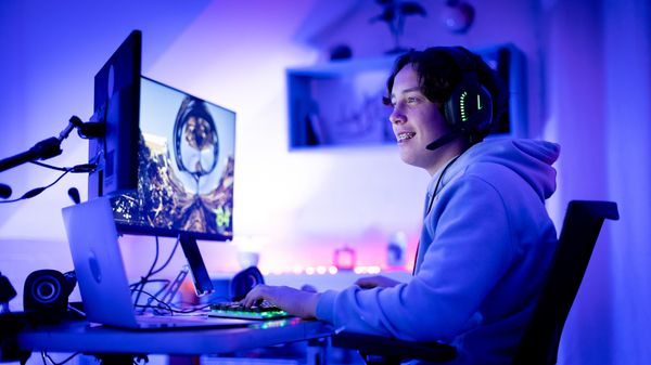 Teen sitting at a computer smiling while gaming