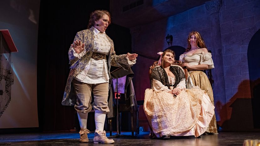 3 actresses in period costumes on stage during theater performance
