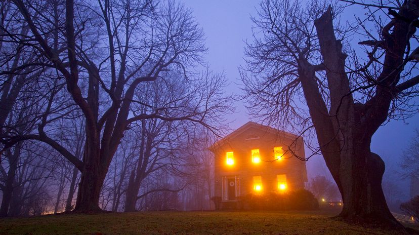 Old stone house with candles in window on foggy gloomy night, Skaneateles, New York.