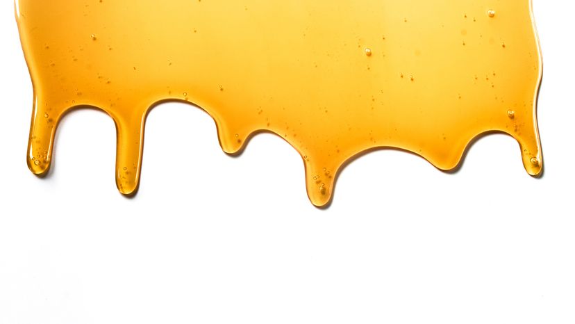 Drops of sweet yellow honey on a white isolated background