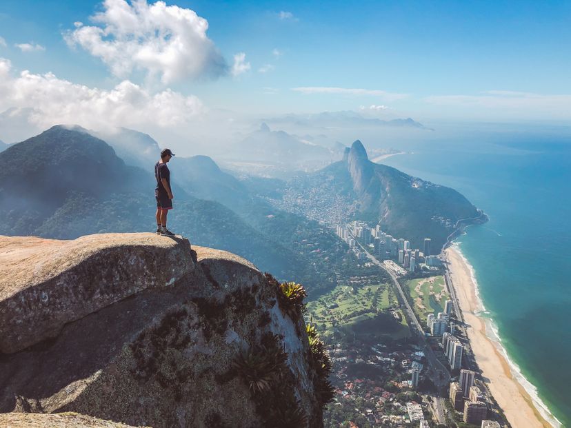 Man standing on the top of Pedra da Gavea watching the views over Rio de Janeiro Brazil