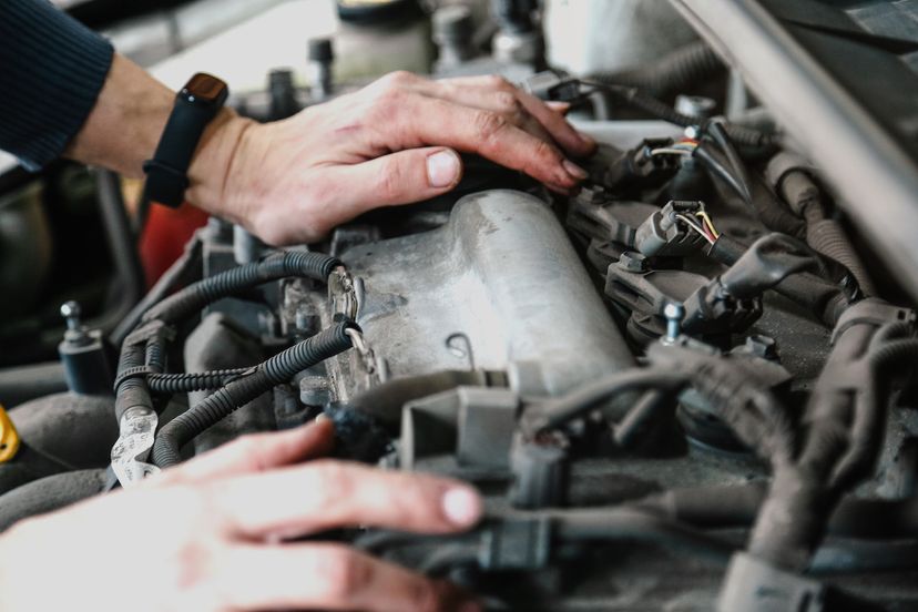 Two hands touch an engine surrounded by metal parts