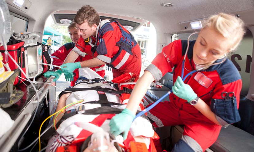 Paramedics using stethoscope on patient in ambulance