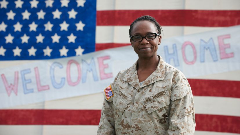 Returning Black soldier standing near American flag welcome home sign