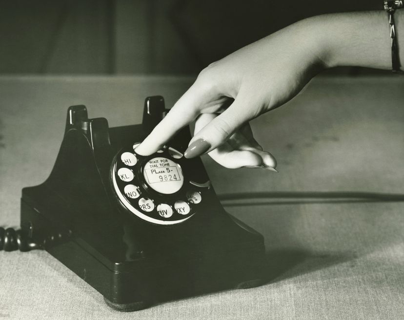 A feminine hand dials on a rotary phone