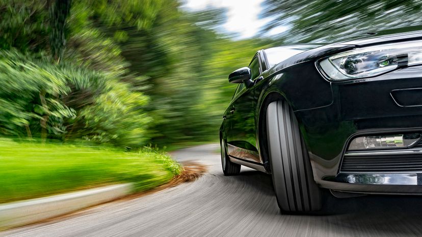 Motion blur shot of black car driving fast in a curve