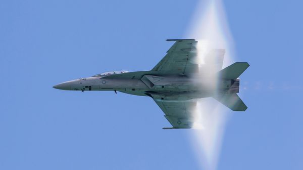 A Navy jet creates visible vapor as it breaks the sound barrier