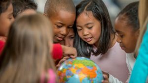 A group of young students gathered around a globe and examining it