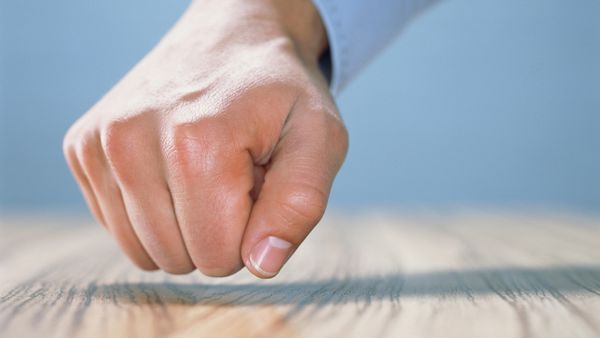 A fist positioned over wood, about to knock