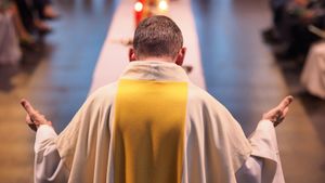 Rear view of a priest with his head bowed and palms extended upward